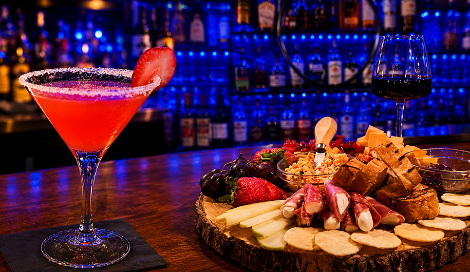 Cocktail, wine, and charcuterie board on bar.