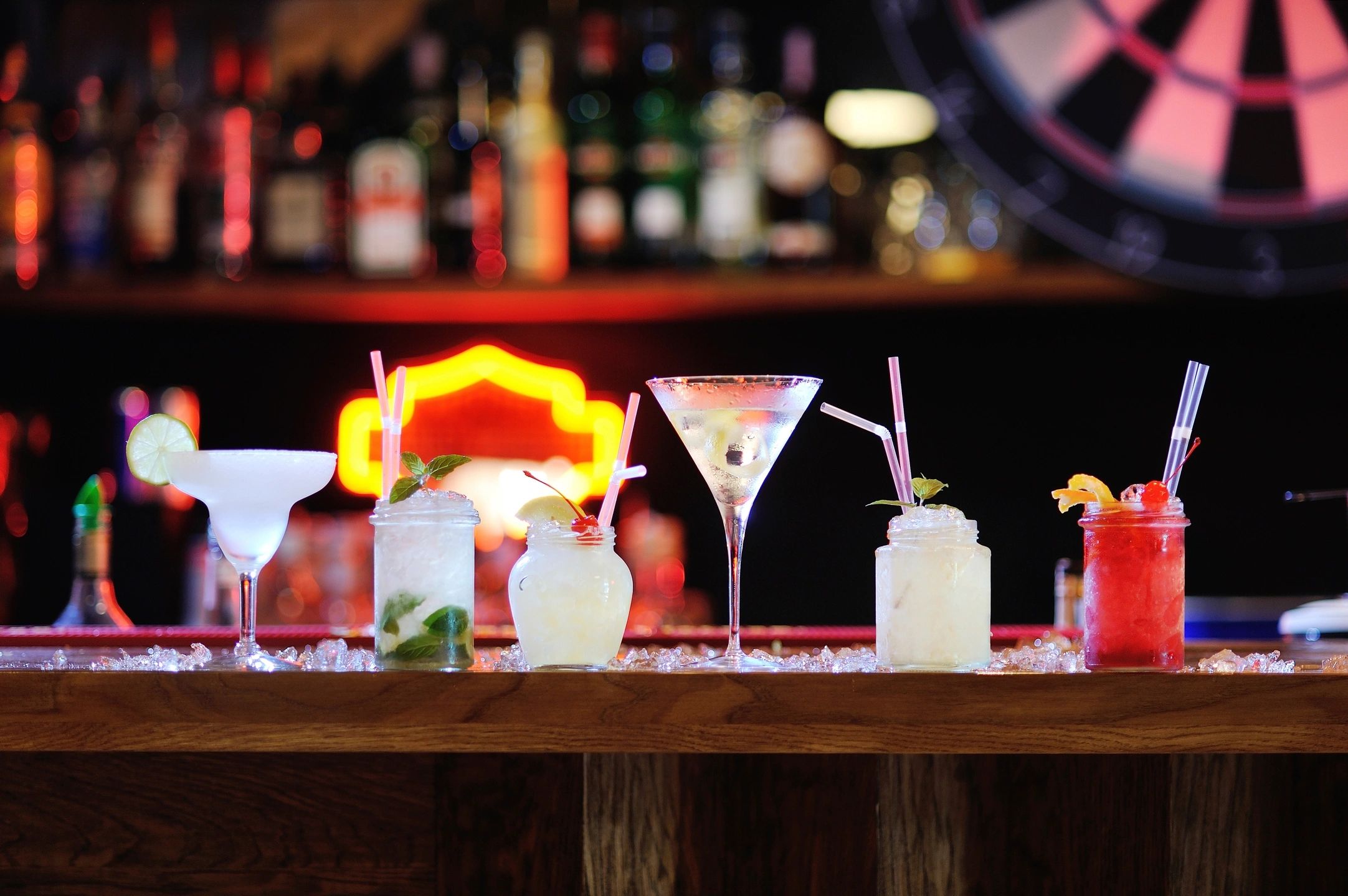 Cocktails on bar counter with neon lights.